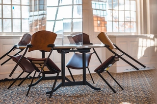 Empty chairs leaned against a table with a clear plastic divider to prevent the spread of airborne disease.